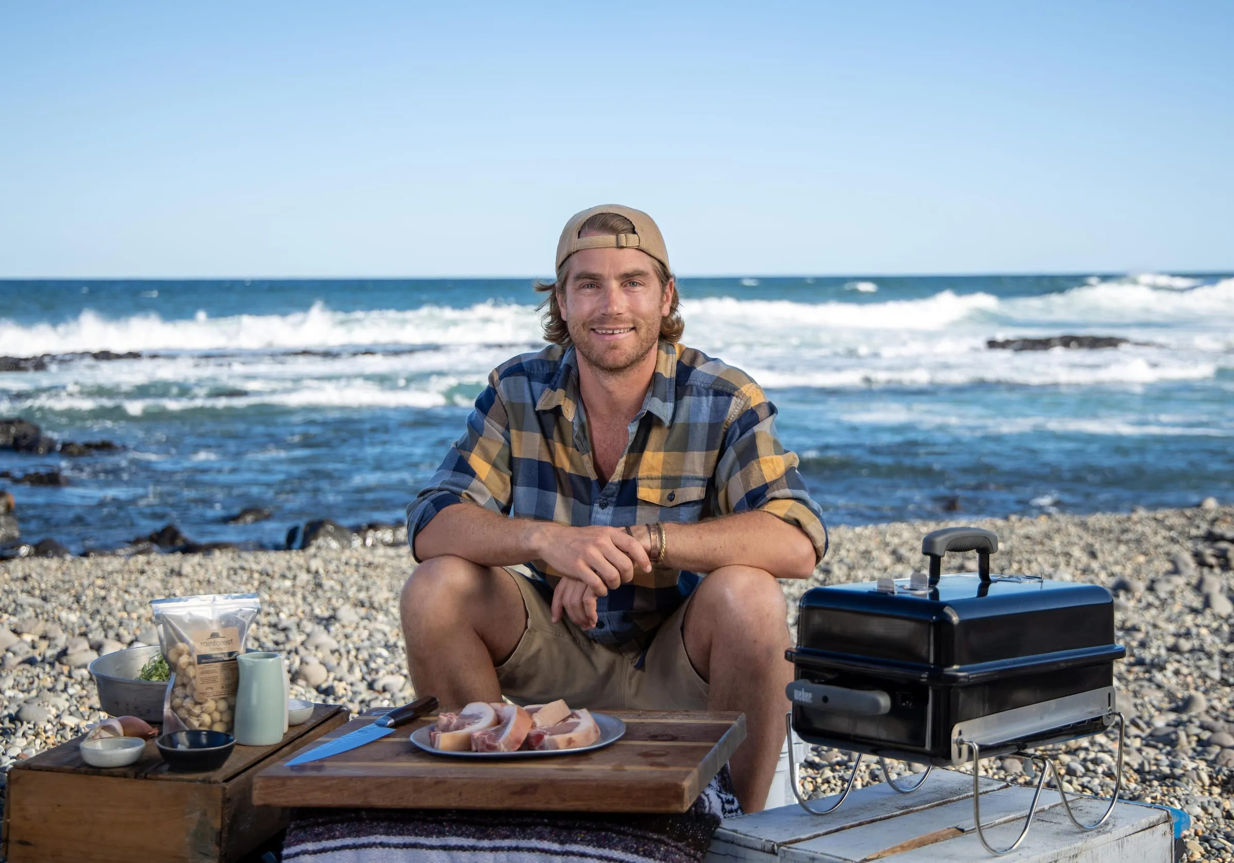 Hayden Quinn cooking on the rocks beside the ocean
