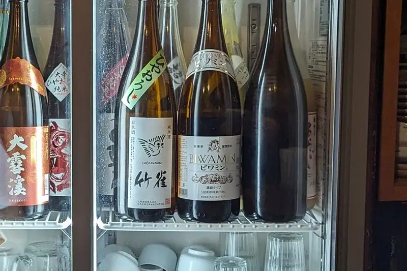 A lit drinks fridge full of bottles at a Kyoto bar